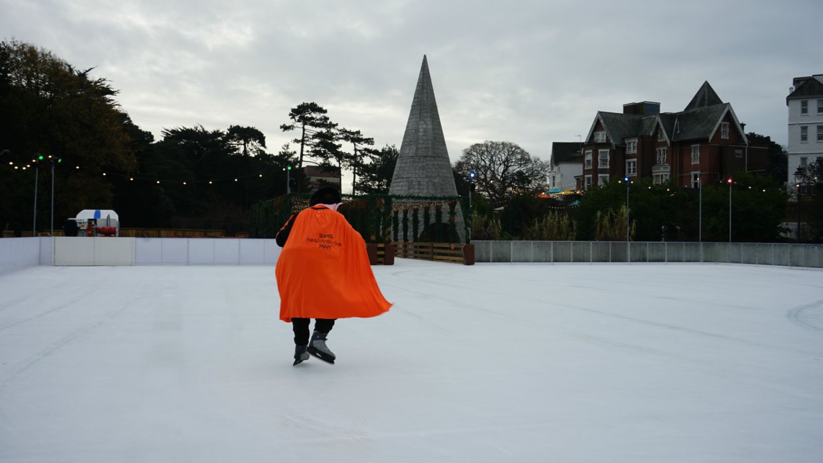 Mr Health on Line in Bournemouth, ice-skating away as his orange cape is blown by the wind